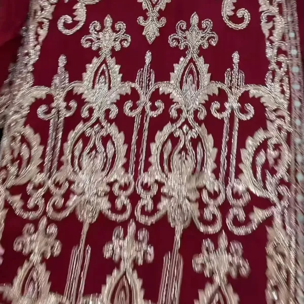 Close-up of cream and silver threadwork on maroon fabric