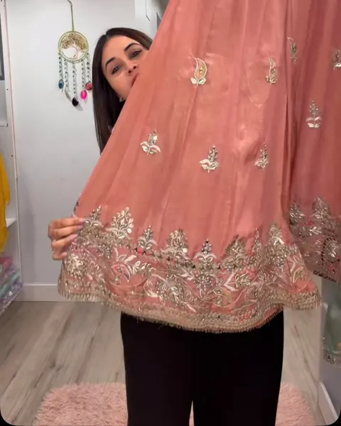 Blush pink outfit with an embroidered border held up in the boutique
