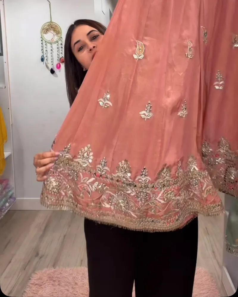 Blush pink outfit with an embroidered border held up in the boutique