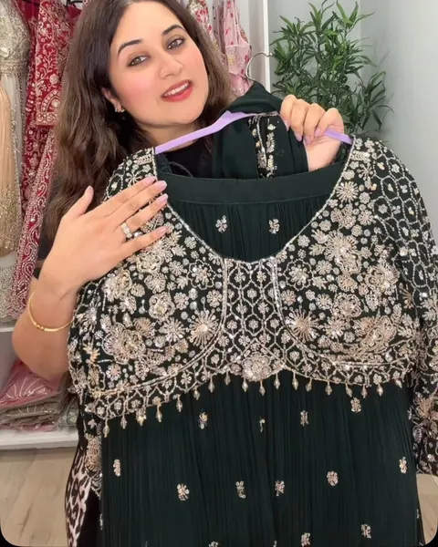 Dark green suit with dense silver and gold embroidery held up in the boutique