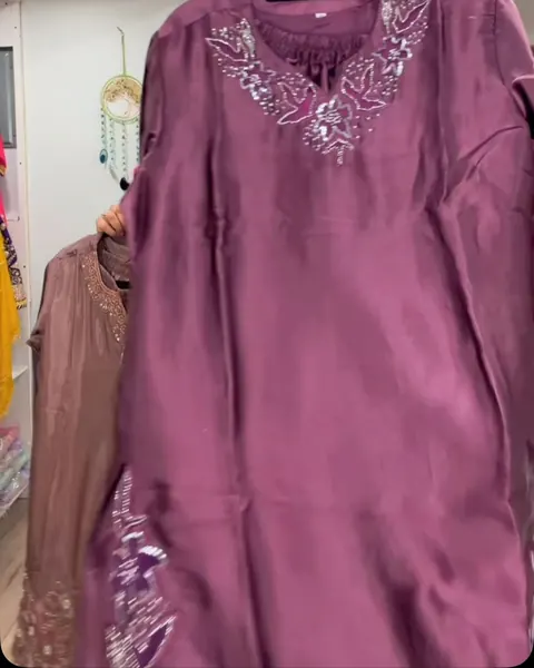 Mauve suit with an embroidered neckline held up in the boutique