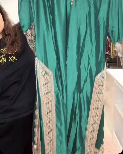 Teal suit with embroidered side panels held up in the boutique